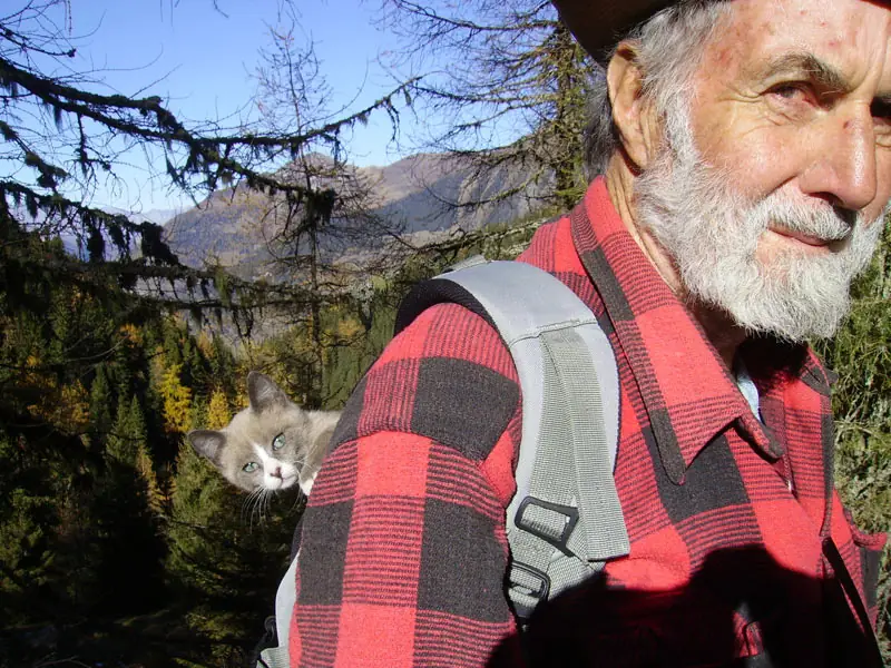Jacques Niederer en montagne, un chat passant la tête hors de son sac à dos